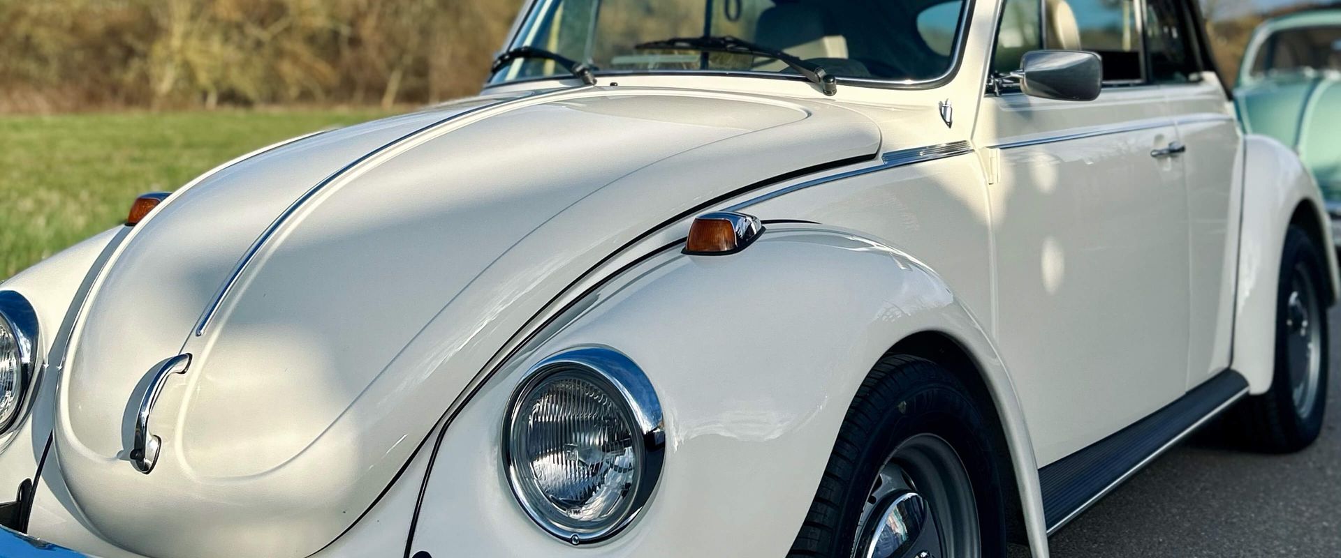 A white Volkswagen Beetle is parked on a road.